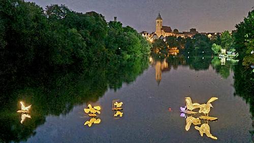 Die beleuchteten Friedenstauben wurden auf dem nächtlichen Neckar.